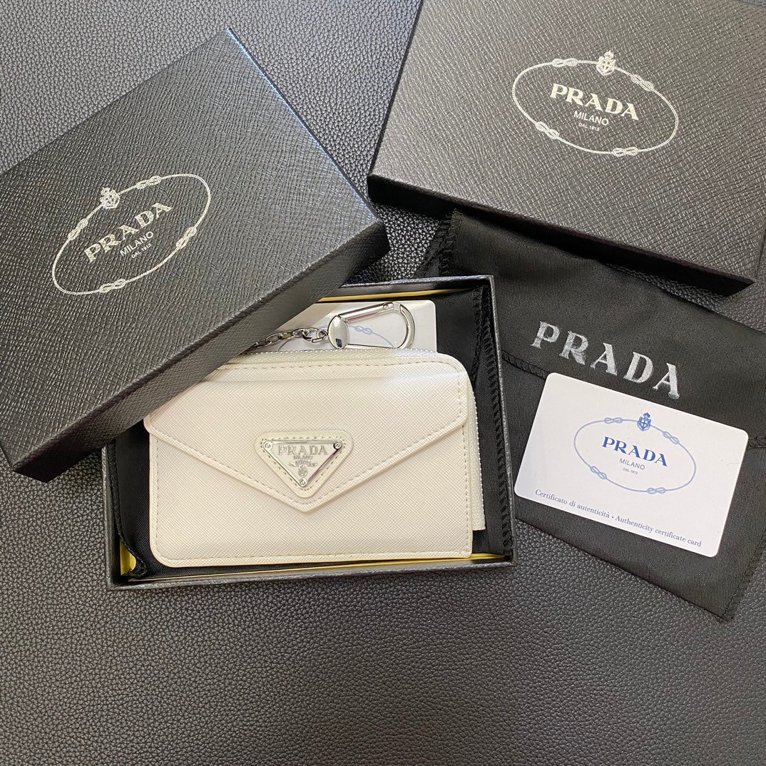 A hand sliding cards into the card slots of a sleek PRADA Classic Card Holder Wallet.